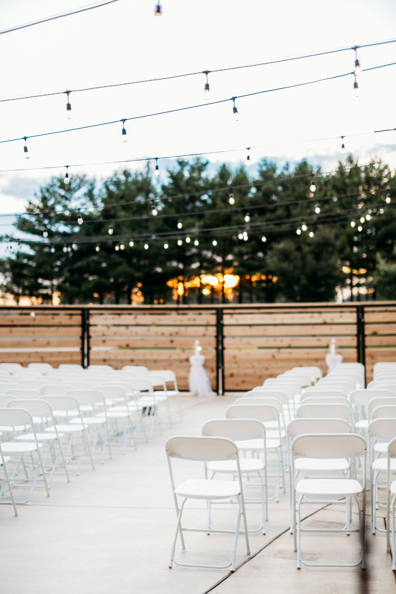 White foldable chairs set up in a fenced open area